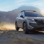 The 2026 Nissan Rogue driving in front of a mountain range